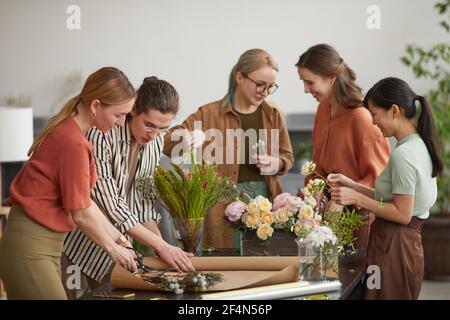 Diverse Gruppe von jungen Floristen arrangieren florale Kompositionen während der Arbeit Im Blumenladen Stockfoto