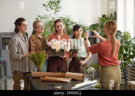 Diverse Gruppe von jungen Floristen Floristen hält florale Zusammensetzung während Posiert für Foto im Blumenladen Stockfoto