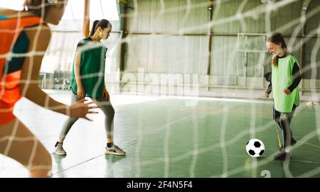 Weibliche Spieler auf der großen Profi-Arena während des Spiels. Innenfoto, Fußballtraining. Junge Fußballspielerin oder Fußballspielerin in Sportbekleidung treten Stockfoto