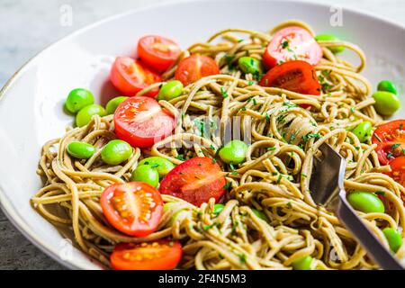 Grüne vegane edamame Pasta mit Tomaten und Bohnen. Pflanzliches Diät-Konzept. Stockfoto