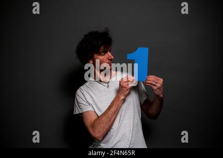 Ein junger Mann in einem weißen T-Shirt mit einem bunten Schaum Nummer eins. Stockfoto