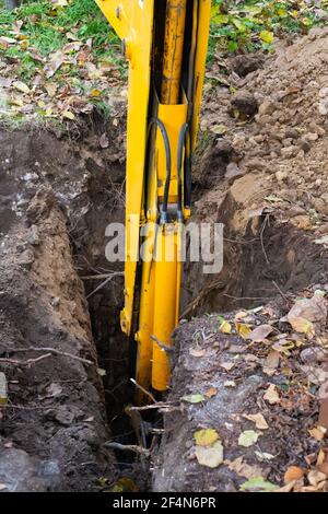 Der Bagger gräbt ein Loch für einen Klärgruben. Arbeiten der Maschine mit dem Boden. Stockfoto