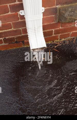 Im Frühjahr läuft aus einem Gebäudeabfluss Wasser aus. Stockfoto