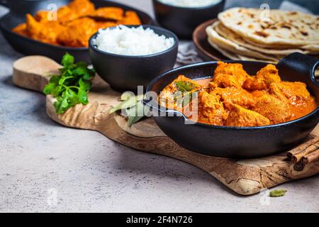 Hühnercurry in einer würzigen Sauce mit Reis und Chapati-Brot, dunkler Hintergrund. Konzept der indischen Küche. Stockfoto