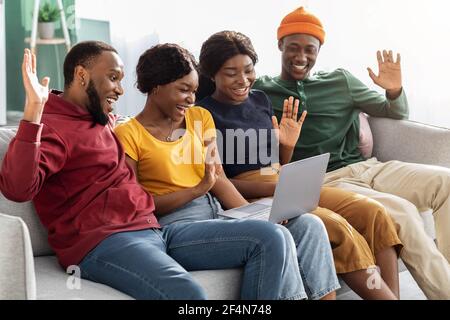 Gruppe von schwarzen Freunden sitzen auf der Couch, mit Videoanruf Stockfoto
