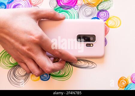 Hand halten Smartphone mit bunten Spiralen Hintergrund Stockfoto