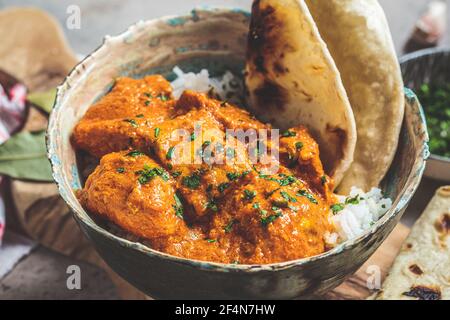 Chicken Tikka Masala in einer würzigen Sauce mit Reis und Chapati Brot, dunkler Hintergrund. Konzept der indischen Küche. Stockfoto