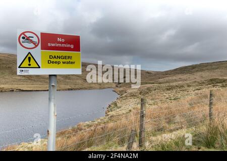 Ein Schild mit Warnung vor tiefem Wasser und der Empfehlung, kein Schwimmen im Readycon Dean Reservoir in der Nähe von Oldham, Lancashire, Großbritannien zu nehmen Stockfoto