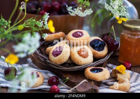 Daumendruck Mandelplätzchen mit Marmelade auf rustikalem Holzhintergrund Stockfoto