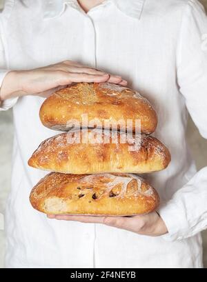 Die Bäckerin hält hausgemachtes Bio-Brot frisch aus dem Ofen. Hausgemachtes Sauerteigbrot. Hausgemachtes Essen. Zubereitung von Speisen. Stockfoto