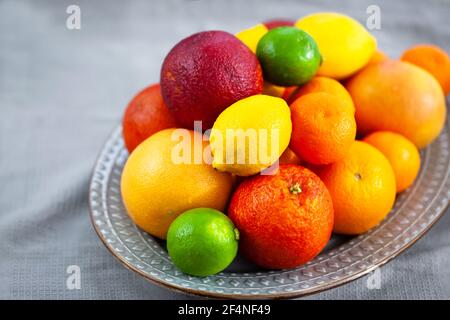 Frische saftige Zitrusfrüchte - Orangen, Mandarinen, Zitronen und Limetten, auf grauem Hintergrund Stockfoto