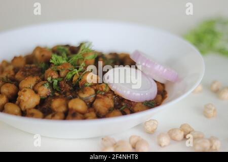 Würzige weiße Kichererbsen-Soße, die über Nacht durch Einweichen von Kichererbsen hergestellt und in einer Soße aus Zwiebeln, Tomaten, Ingwer, Knoblauch und Gewürzen gekocht wird. Schuss auf weißem Rücken Stockfoto