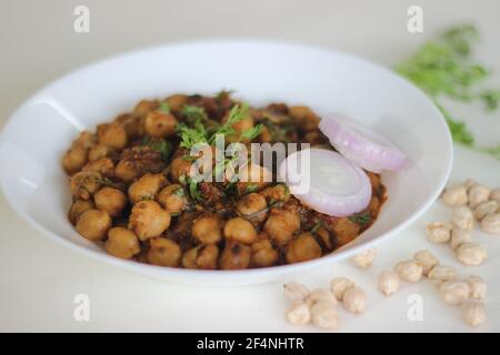 Würzige weiße Kichererbsen-Soße, die über Nacht durch Einweichen von Kichererbsen hergestellt und in einer Soße aus Zwiebeln, Tomaten, Ingwer, Knoblauch und Gewürzen gekocht wird. Schuss auf weißem Rücken Stockfoto