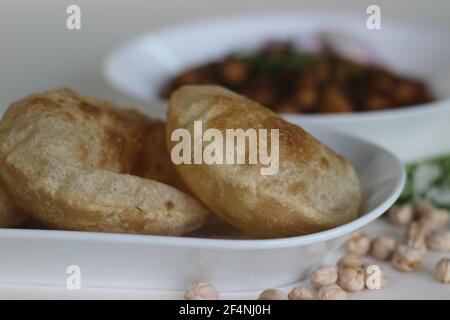 Flauschige Vollkorn gebratenes indisches Fladenbrot, serviert zusammen mit würziger Kichererbsen-Soße. Lokal bekannt als Chole puri. Aufnahme auf weißem Hintergrund Stockfoto