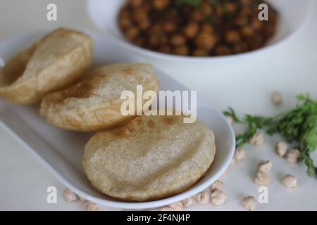 Flauschige Vollkorn gebratenes indisches Fladenbrot, serviert zusammen mit würziger Kichererbsen-Soße. Lokal bekannt als Chole puri. Aufnahme auf weißem Hintergrund Stockfoto