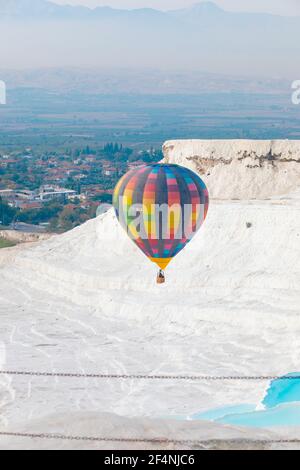 Helle bunte Heißluftballon fliegen über weißen Berg Pamukkale in der Türkei, vertikale Aufnahme. Stockfoto
