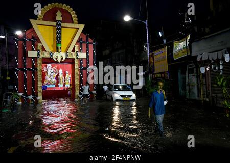 Die Menschen gehen an einem Durga-Puja-Pandal vorbei, das während einer Sturzflut nach schwerem spätem Monsunregen in Kalkutta, Indien, fast in Wasser getaucht ist. Stockfoto