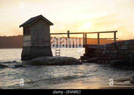 Watsons Bay, Sydney, NSW Australien - Sonnenuntergang hinter einer kleinen Hütte und Brücke in Camp Cove Beach Stockfoto