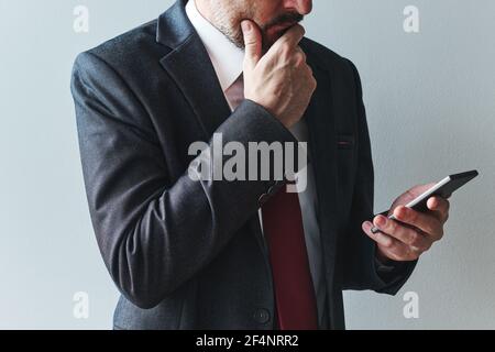 Notleidende Unternehmer mit Handy, Lesen einer E-Mail oder SMS. Elegante Geschäftsfrau in Anzug mit Kommunikationstechnik. Stockfoto