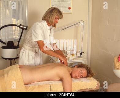 Beautican tut Rückenmassage auf junge Frau, Winkfield, Berkshire, England, Vereinigtes Königreich Stockfoto