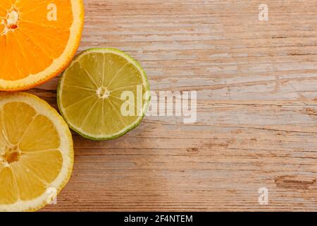 Orangen, Limetten und Zitronen Rutschen auf Holztisch Blick von oben. Wunderschön Hintergrund mit frischem Obst halb geschnitten.gesunde Ernährung Vitamin C.Sommer tropic Stockfoto