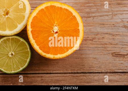 Orangen, Limetten und Zitronen Rutschen auf Holztisch Blick von oben. Wunderschön Hintergrund mit frischem Obst halb geschnitten.gesunde Ernährung Vitamin C.Sommer tropic Stockfoto