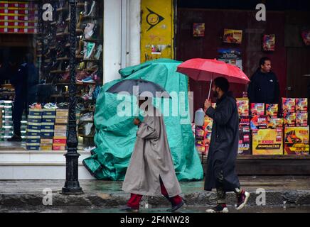 Srinagar, Indien. März 2021, 22nd. Pendler halten Regenschirme, wie sie entlang einer Straße gehen während der Regenfälle in Srinagar.die meteorologische Abteilung (MET) hat vier Tage nass Zauber über das Kaschmir-Tal vom 21. März bis 24. März mit der großen Intensität der Vorhersage erwartet am 22. März und 23. März vorhergesagt. (Foto von Saqib Majeed/SOPA Images/Sipa USA) Quelle: SIPA USA/Alamy Live News Stockfoto