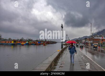 Srinagar, Indien. März 2021, 22nd. Ein Pendler hält einen Regenschirm, während er entlang einer Straße während der Regenfälle in Srinagar geht.die meteorologische Abteilung (MET) hat vier Tage nassen Zauber über das Kaschmir-Tal von März 21 bis März 24 vorhergesagt, mit der großen Intensität der Vorhersage am 22. März und März 23 erwartet. (Foto von Saqib Majeed/SOPA Images/Sipa USA) Quelle: SIPA USA/Alamy Live News Stockfoto