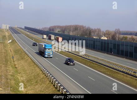 Fahrzeuge, die auf der Autobahn fahren. Sichtbare Schallschutzbarrieren trennen die Autobahn vom Wohngebiet. Stockfoto