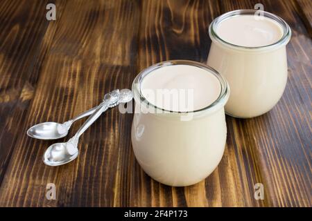 Hausgemachte ryazhenka in den Gläsern auf dem braunen Holzhintergrund. Fermentiertes Milchprodukt. Nahaufnahme. Stockfoto