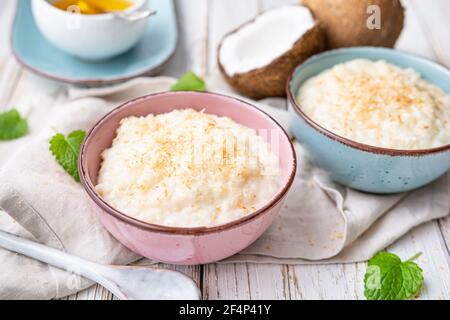 Süßer und cremiger Kokosnusspudding mit Honig, gekrönt mit geriebener und gerösteter Kokosnuss in einer Keramikschale Stockfoto