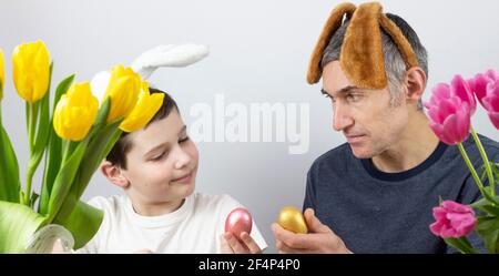 Ostereier. Frohe Ostern Karte. Mehrfarbige Ostereier. Ostern. Ostereier auf weißem Holzhintergrund. Ostereier. Kaninchenohren. Für Text platzieren Stockfoto