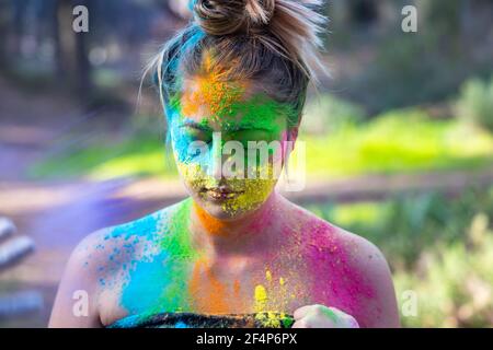 Junge attraktive Frau auf dem Holi Farbe Festival der Farben im Park. Spaß im Freien. Mehrfarbige Puder färbt das Gesicht. Nahaufnahme im Hochformat. Stockfoto