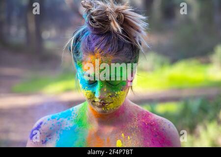 Junge attraktive Frau auf dem Holi Farbe Festival der Farben im Park. Spaß im Freien. Mehrfarbige Puder färbt das Gesicht. Nahaufnahme im Hochformat. Stockfoto