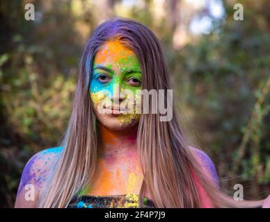 Junge attraktive Frau auf dem Holi Farbe Festival der Farben im Park. Spaß im Freien. Mehrfarbige Puder färbt das Gesicht. Nahaufnahme im Hochformat. Stockfoto