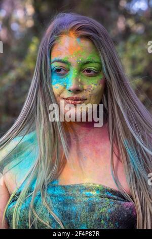 Junge attraktive Frau auf dem Holi Farbe Festival der Farben im Park. Spaß im Freien. Mehrfarbige Puder färbt das Gesicht. Nahaufnahme im Hochformat. Stockfoto