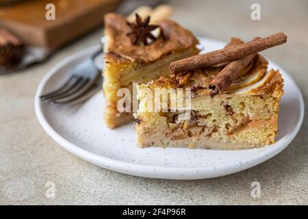 Zwei Stück Apfelkuchen mit Zimt auf einem Teller, heller Betonhintergrund. Grießkuchen mit Apfel und Gewürzen. Hausgemachter Mannik. Selektiver Fokus. Stockfoto