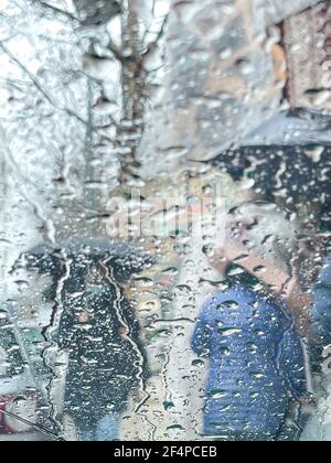 Regen auf einem Fenster, Blick auf Silhouetten Menschen in einer Straßenszene Stockfoto