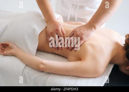 Männlicher Masseur massiert zurück von jungen unkenntlich Frau liegend auf Massageliege Tisch. Stockfoto