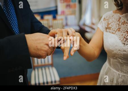 Flacher Fokus eines Bräutigams, der einen Ring auf die legt Der Finger der Braut während der Feier Stockfoto