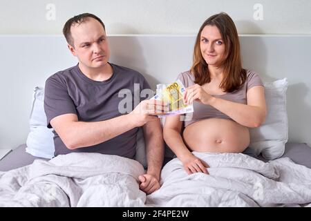 Mann, der schwangere Frau Geld in Euro im Bett gibt? Konzept Stockfoto
