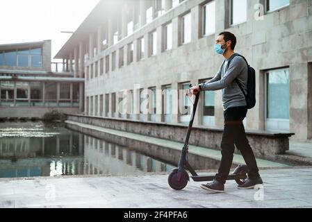 Stilvoller Mann zu Fuß in der Nähe Elektroroller auf der Straße Stockfoto