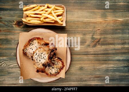 Gegrillte Schweinekoteletts mit pommes auf rustikalem Holz Tabelle Stockfoto