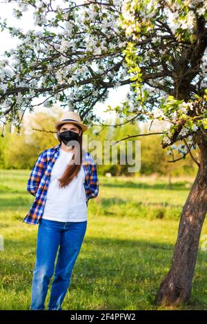 Portrait einer jungen Frau mit schwarzer Gesichtsmaske. Staubschutz gegen Viren. Coronavirus-Pandemiezeit. Mädchen im amerikanischen Landhausstil. Lifestyle c Stockfoto