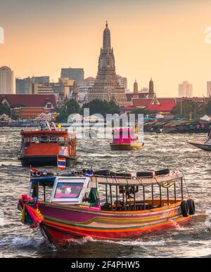Boote auf dem Chao Phraya Fluss und Wat Arun, der Tempel der Morgenröte, ein wichtiger buddhistischer Tempel und ein berühmtes Touristenziel in Bangkok Yai Bezirk Stockfoto