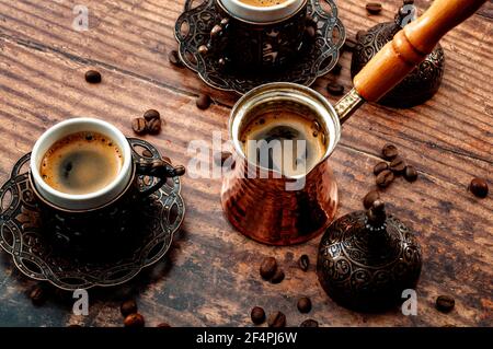 Traditionelles türkisches Kaffeeset, mittelöstliche Kultur und arabisches Traditionskonzept mit Metallbechern, Kupfertopf mit Holzgriff und Roas Stockfoto