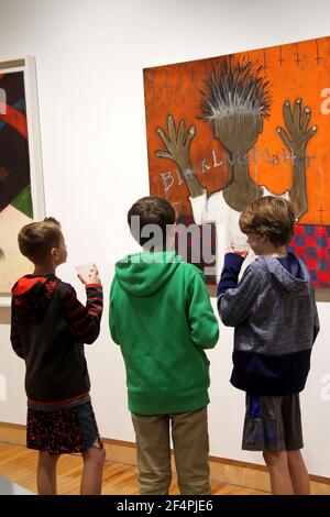 Junge Jungs vor einem Stück sozialer Kunst in einer Galerie in den USA Stockfoto