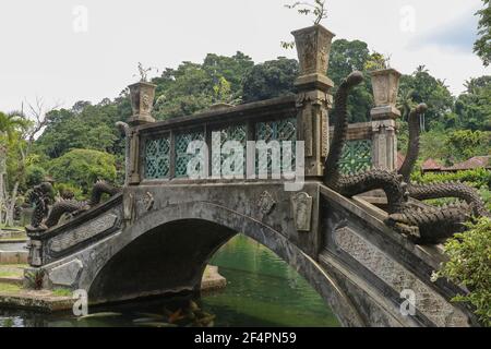 Eine künstliche Brücke mit vier Statuen von Drachen mit verdrehten Schwänzen, Tirta Gangga Park, Karangasem Region der Bali Insel, Indonesien Stockfoto