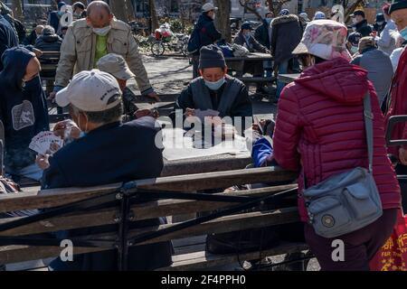 New York, NY - 22. März 2021: Asiatisch-amerikanische New Yorker verbringen einen ruhigen, warmen Frühlingstag im Columbus Park und spielen Karten, chinesisches Schach oder genießen einfach nur den Tag Stockfoto