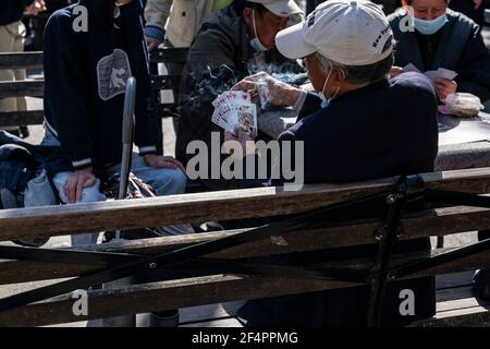 New York, Usa. März 2021, 22nd. Asiatisch-amerikanische New Yorker verbringen einen ruhigen, warmen Frühlingstag im Columbus Park und spielen Karten, chinesisches Schach oder genießen einfach den Tag in New York am 22. März 2021. Park sieht am nächsten Tag nach einer großen Kundgebung gegen asiatisch-amerikanische Hassverbrechen völlig friedlich und anders aus. Die einzige Erinnerung sind Blumen und Poster an der Skulptur von Dr. Sun Yat-sen. (Foto von Lev Radin/Sipa USA) Quelle: SIPA USA/Alamy Live News Stockfoto